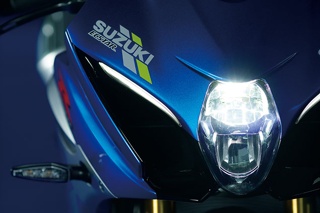 Detailaufnahme des Scheinwerfers eines blauen Suzuki Motorrads mit dem Logo und sportlichem Design.
