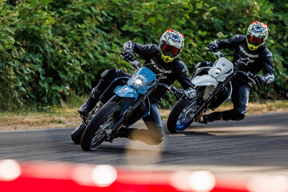 Zwei Motorradfahrer in Schutzkleidung fahren dynamisch auf einer kurvenreichen Strecke mit sportlichen Motorrädern.