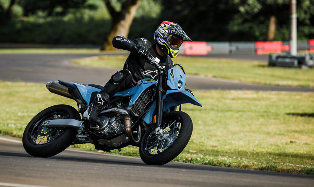Ein Motorradfahrer in Schutzkleidung fährt mit einem blauen Motorrad auf einer Rennstrecke.